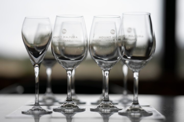 Six empty wine glasses on a reflective surface, with blurred background.
