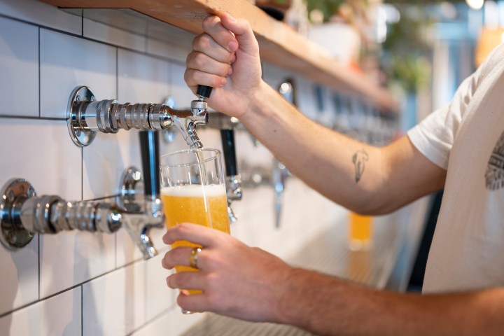 Person pouring beer from a tap into a glass.