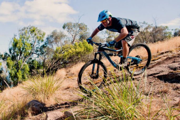 a man riding a bike down a dirt road